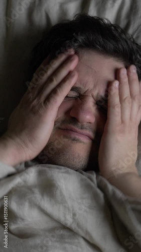 middle-aged man sleeps in bed and wakes up with a severe migraine, vertical video