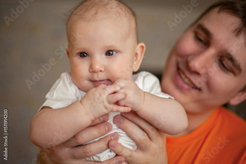 young dad happily holds his two month old newborn baby at home