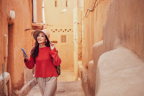 Foto Young woman tourist using smartphone while exploring ancient Moroccan city, famo