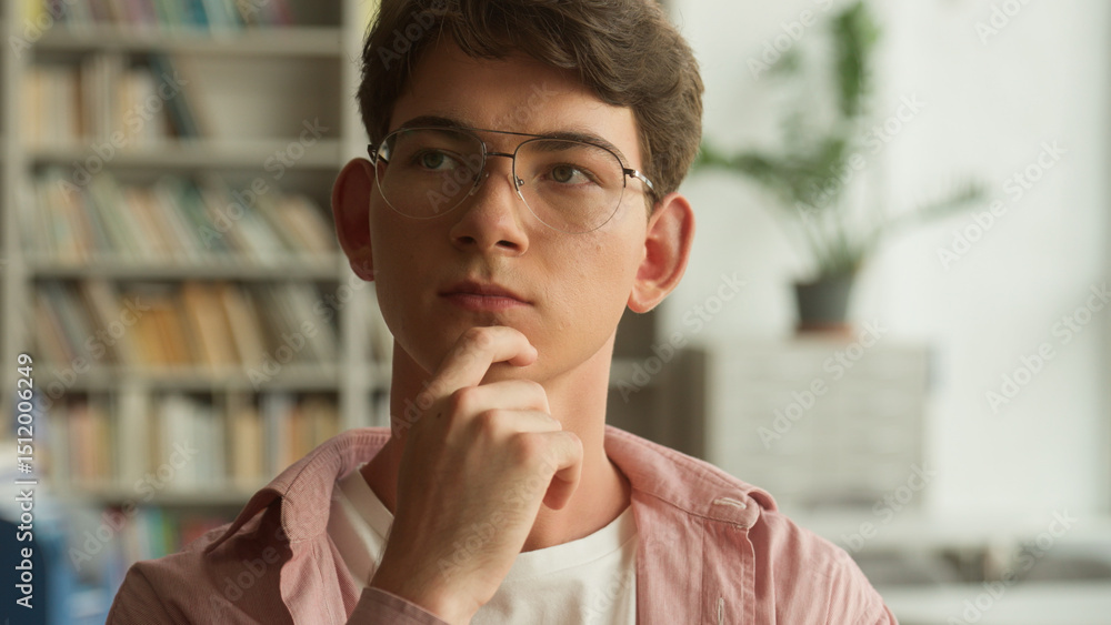 Naklejka premium Close up portrait Caucasian teenager guy pensive looking around thinking ponder choosing book in school college academy university library man teen boy think thoughtful education studying concept