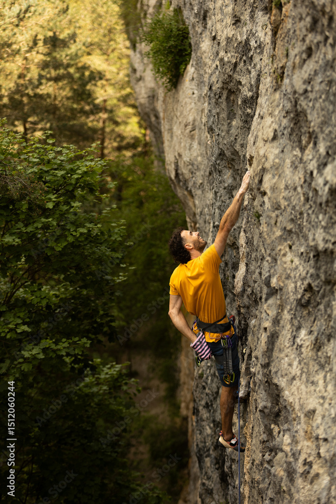 A man in a yellow shirt is climbing a rock wall A man in a yellow shirt is climbing a rock wall