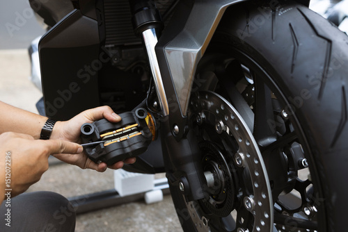 Mechanic hand replacing motorcycle brake pads with close-up on disc brake system