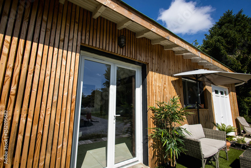 une petite maison moderne vu de l'extérieur les murs sont en bardage bois, le ciel est bleu