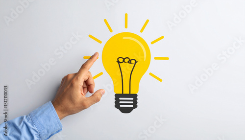 Man hand pointing at drawn yellow light bulb, gray background
