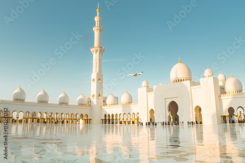 Luxury private jet landing above the iconic Sheikh Zayed Grand Mosque in Abu Dhabi. Modern aviation and Islamic architecture highlights opulence, travel, and cultural landmarks in the UAE capita