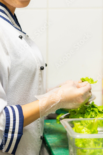 Asian female chef preparing fresh lettuce in professional kitchen