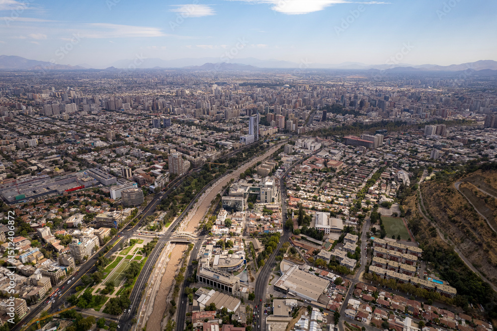 Fototapeta premium Aerial daytime view of Santiago showing the Mapocho River, Providencia district, the Telefónica building, and surrounding neighborhoods stretching toward the horizon. Captured from a drone 
