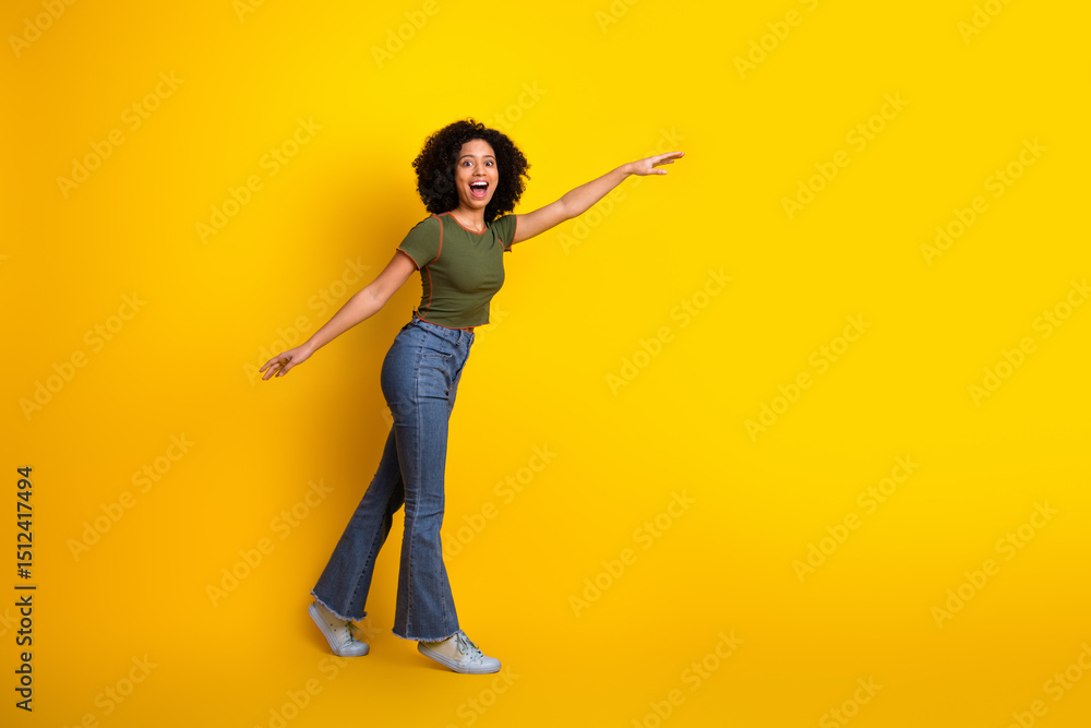 Obraz premium Portrait of a cheerful young woman in casual attire enjoying a playful moment against a vibrant yellow background