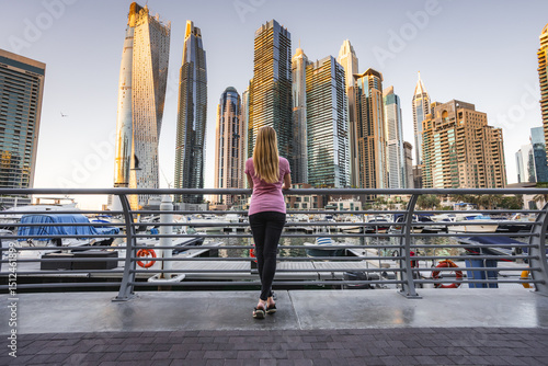 Photography Woman looking up in awe at the towering skyscrapers of Dubai Marina