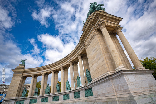 A captivating view of Heroes' Square in Budapest, Hungary, showcasing the iconic Millennium Monument and the surrounding statues, set against a clear blue sky