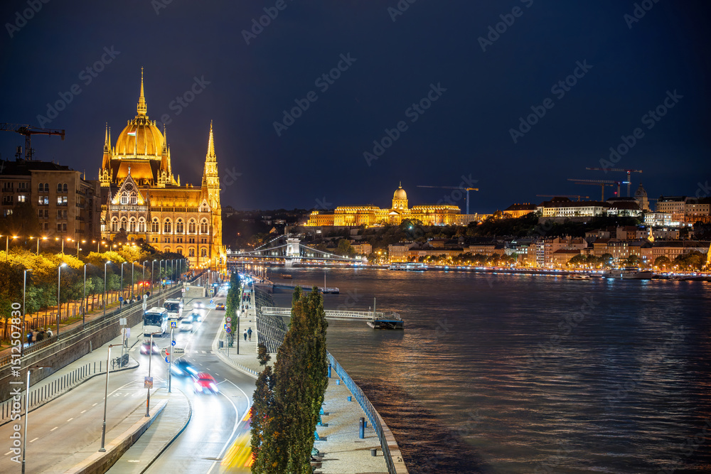 Fototapeta premium Night view of the Chain Bridge and Hungarian Parliament in Budapest, Hungary, illuminated against the night sky, with cars driving along the road
