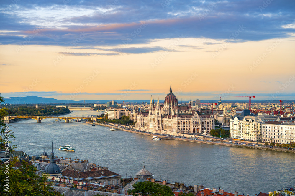 Obraz premium A stunning view of the Hungarian Parliament before sunset, with beautiful yellow tones and wispy clouds enhancing the charm of Budapest, capturing the city's essence as day transitions into evening