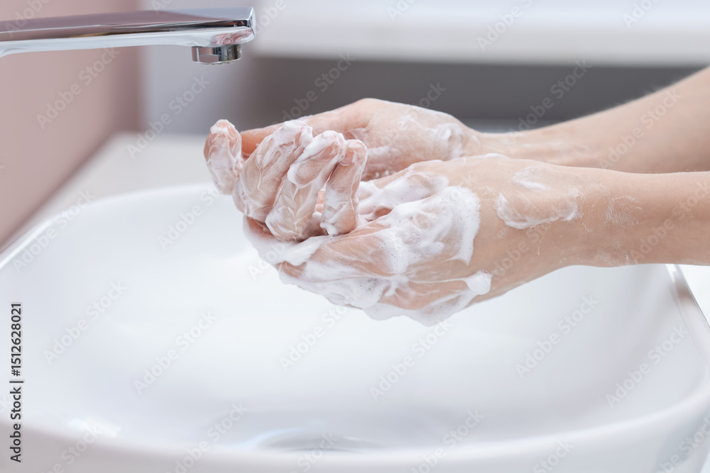 Fototapeta premium Woman washing hands at sink in bathroom, closeup