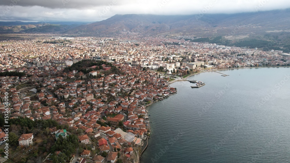 Fototapeta premium Historic Samuel's fortress overlooks serene coastal town with modern architecture under cloudy sky, Ohrid 