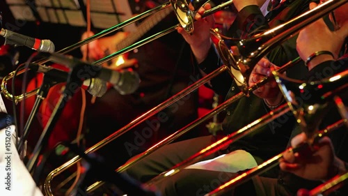 A vibrant jazz scene featuring musicians playing trombones. Microphones capture the lively atmosphere. Close-up of the trombone section