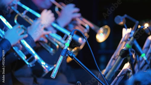 The big band's trumpet section. A vivid scene of musicians playing trumpets in a dimly lit hall. Focus on the microphone, musicians blurred