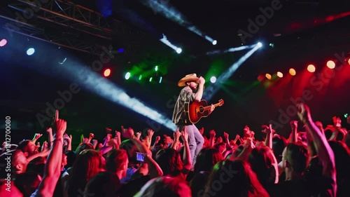 Country music artist performs on stage in front of excited crowd during live concert at outdoor venue