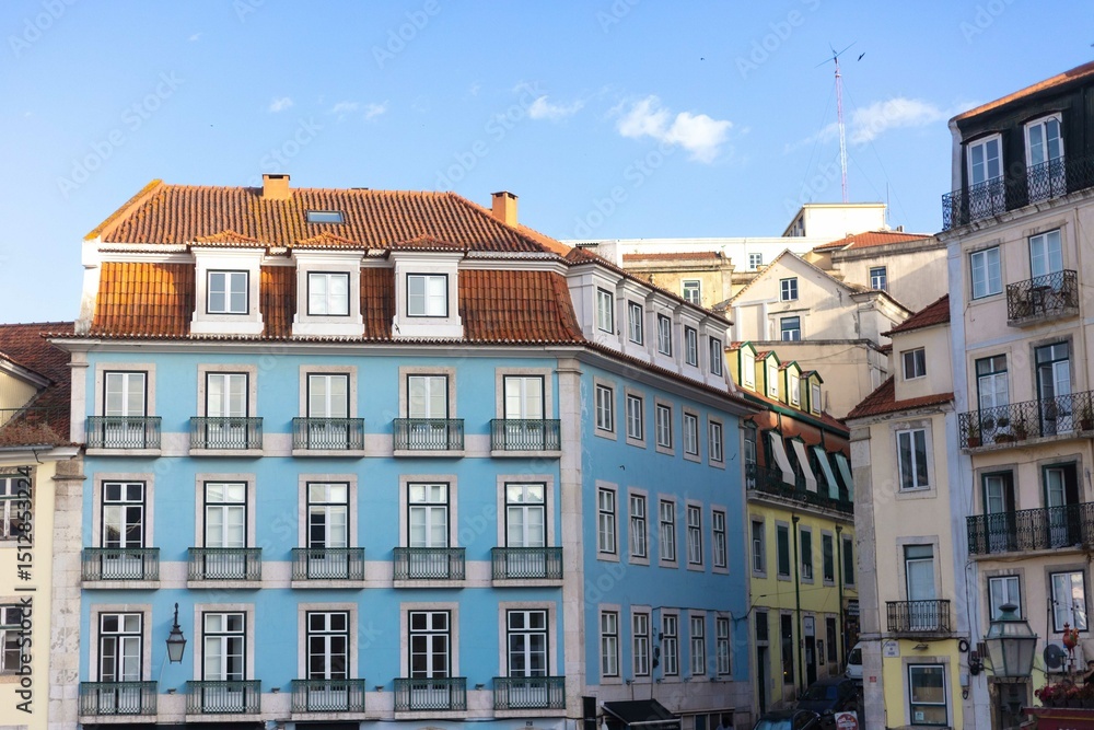 Fototapeta premium A charming blue building with traditional Portuguese architecture stands in a sunny street of Lisbon, Portugal, surrounded by colorful neighboring buildings and ornate wrought-iron balconies.