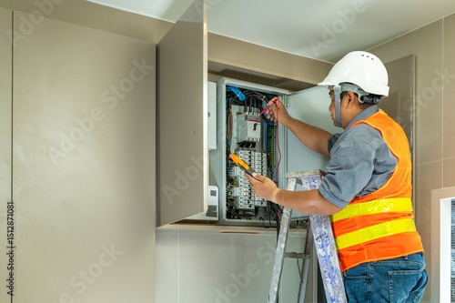Professional Electrician Installing and Inspecting Electrical Panel in Indoor Wall Electrical Cabinet with Tools and Safety Gear