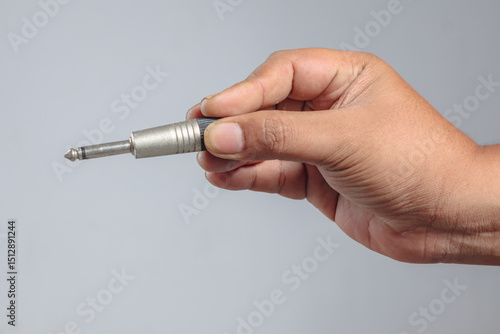 Hand holding quarter inch audio plug with metal jack in horizontal view