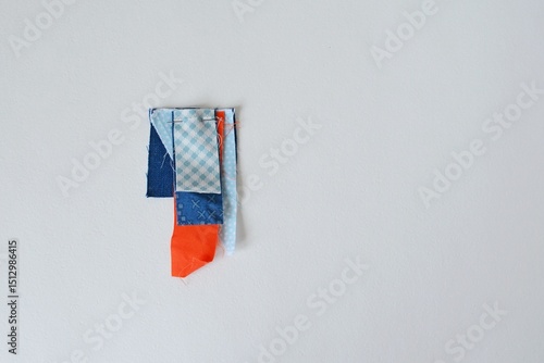 Tiny fabric scraps and sewing pin on white background