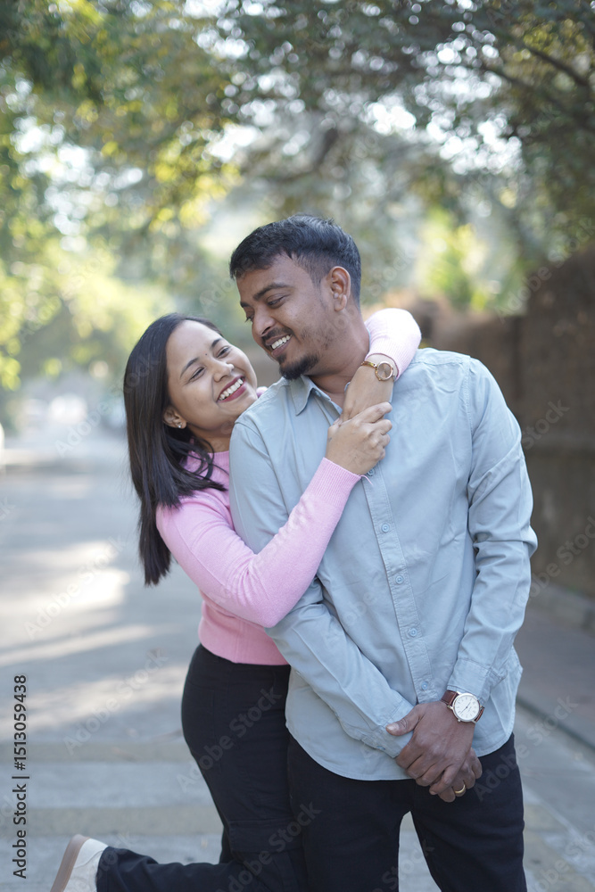 Obraz premium A joyful young couple sharing a loving moment on a peaceful street surrounded by greenery