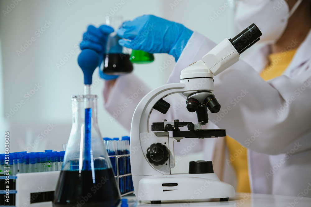 A scientist conducts chemical research in a laboratory using a microscope and pipette, analyzing liquids for medical and biotechnology development. A scientist conducts chemical research in a laboratory using a microscope and pipette, analyzing liquids for medical and biotechnology development.