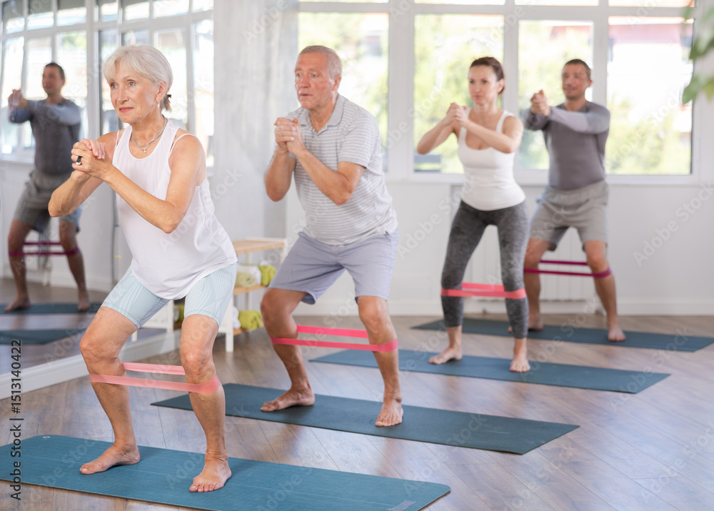 During training, woman applies complication of exercise, squats with limiter, rubber band, on her legs. Concept of active lifestyle, physical activity During training, woman applies complication of exercise, squats with limiter, rubber band, on her legs. Concept of active lifestyle, physical activity