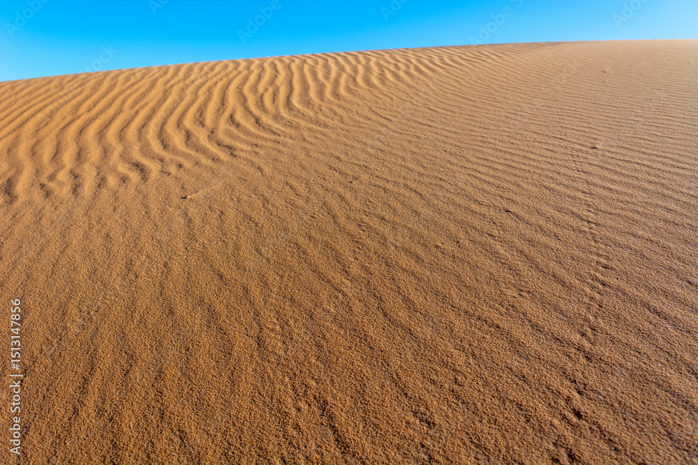 Naklejka premium A sandy desert with a blue sky in the background