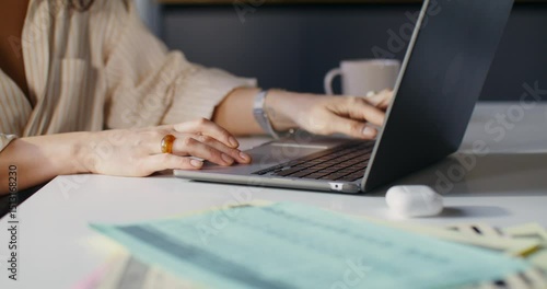 A woman opens her laptop while starting work in the office. Close-up of her hands, unrecognizable person