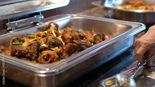 meatballs in the buffet Deep fried foods such as Chicken Drumsticks, Meatballs and Torfu in stainless steel trays, being kept warm inside a glass display counter cabinet. In a local buffet restaurant.