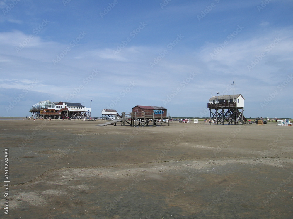 Fototapeta premium Pfahlbauten am Sandstrand von Sankt Peter-Ording an der Nordseeküste