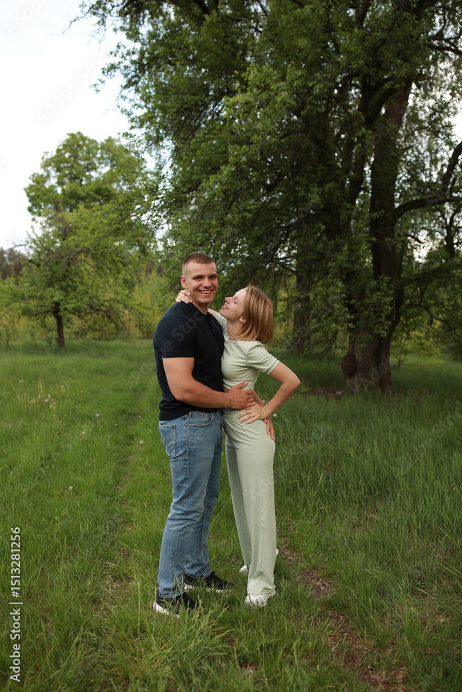 Obraz premium Young couple embracing affectionately in a lush green setting Their genuine smiles and close physical connection evoke a sense of love joy and emotional intimacy ideal for romantic lifestyle content