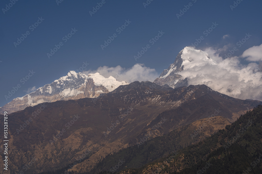 A breathtaking view of the snow-capped peaks of Annapurna I. and Annapurna South when the clouds softly hug the mountains in great Himalayas in Nepal. A breathtaking view of the snow-capped peaks of Annapurna I. and Annapurna South when the clouds softly hug the mountains in great Himalayas in Nepal.