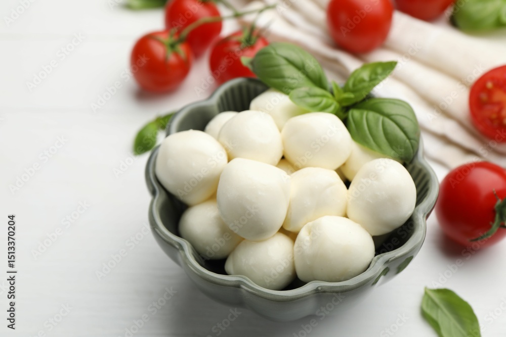 Tasty mozzarella cheese balls, tomatoes and basil on white wooden table, closeup Tasty mozzarella cheese balls, tomatoes and basil on white wooden table, closeup