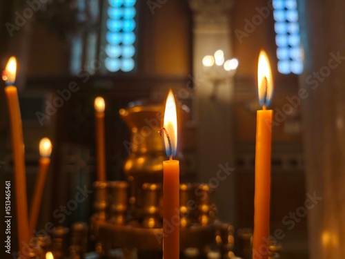 Tablou pe pânză Closeup view of lit Orthodox prayer candles in a brass holder inside a dimly lit church, casting a warm, serene glow and creating a peaceful, spiritual atmosphere