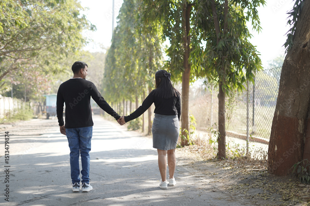 Fototapeta premium A young couple lovingly embracing while standing on a quiet, tree-lined path on a sunny day