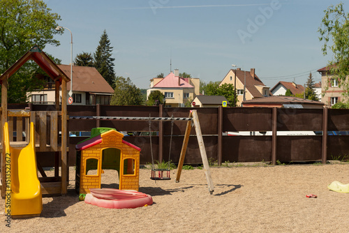 Wallpaper Mural A vibrant and colorful playground featuring a fun slide, swings, and a playhouse set amidst charming residential houses Torontodigital.ca