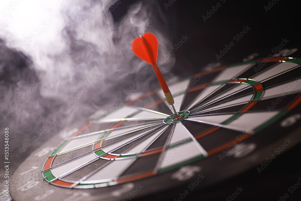 Obraz premium Red Dart Hitting Bullseye on Dartboard with Smoke Effects