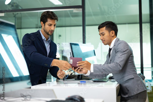 receptionist at desk in airport : Asian man receptionist helping hispanic male traveler with passport for check in at terminal counter
