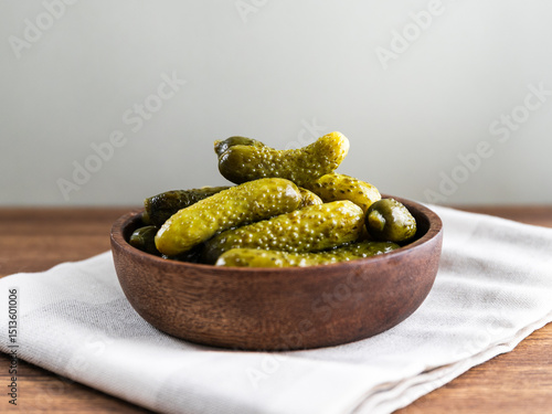 Marinated pickles or gherkins served in a wooden bowl on a table