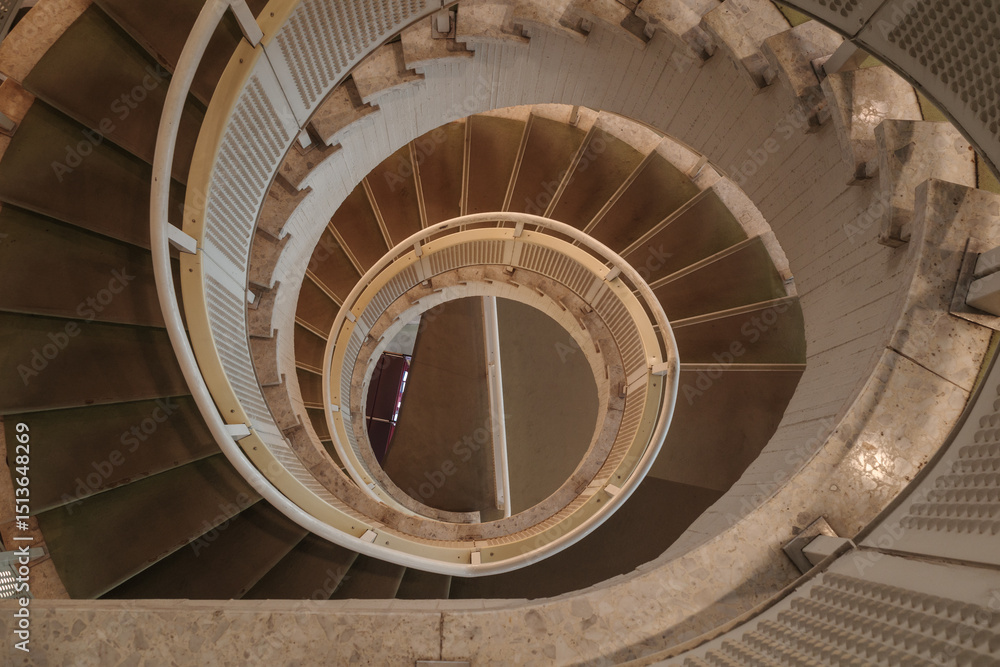 Fototapeta premium A high-angle photograph captures the mesmerizing, abstract patterns of a winding spiral staircase as it descends. 