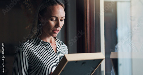 Принти на полотні Woman, photo frame and sad by window with memory, mourning and regret or loss of loved one at home