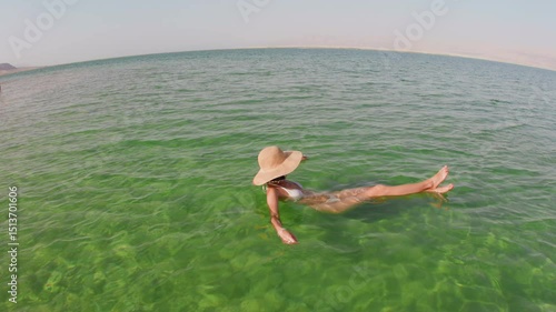 young girl enjoying swimming in dead sea. woman undergoing thalassotherapy enjoying calm swimming in clear green waters of dead sea. beautiful woman floating in dead sea