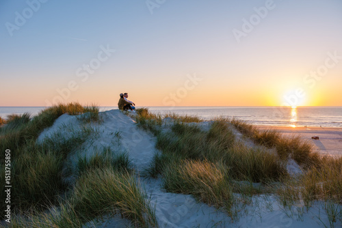 Slika na platnu Couple enjoying a romantic sunset on a sandy dune in Denmark by the North Sea