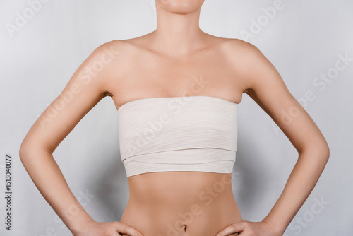 Young Woman Shows Off Elastic Bandage on Chest After Breast Lift Surgery: Recovery Journey Begins.