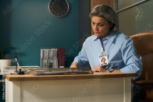 Foto Middle aged Caucasian woman with gray hair wearing identification badge sitting