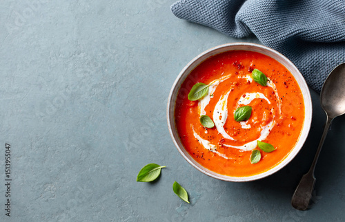 Delicious tomato cream soup in bowl on grey stone background, space for text. Top view.