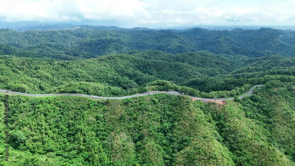 Aerial view highway Drone flying above winding road during sunlight, Winding asphalt road through tropical rainforest. countryside landscape. Landmark tourist attractions in Nan Province, Thailand. Aerial view highway Drone flying above winding road during sunlight, Winding asphalt road through tropical rainforest. countryside landscape. Landmark tourist attractions in Nan Province, Thailand.
