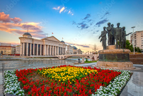 Beautiful spring cityscape of the capital of North Macedonia - Skopje with the Archaeological Museum. View of the Bridge of Arts and monuments. Colorful flowers in the foreground.